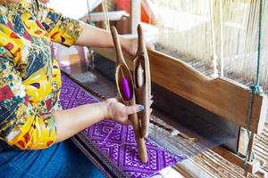 A weaver holding a bobbin with thread for weaving traditional patterns with a hand loom, the wisdom of villagers in the north of Thailand.soft and selective focus. photo