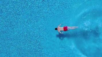 Aerial view of man in red shorts swims in the pool video