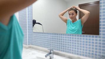 bonito mujer despide y estilo pelo en frente de baño espejo video