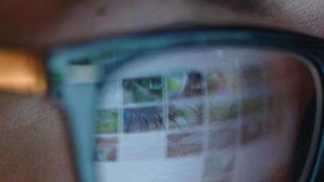 mulher dentro óculos olhando em a monitor e surfar Internet às noite. a monitor tela é refletido dentro a óculos video