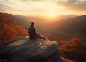 Image of woman sits on rock and watches sunset photo