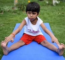 asiático inteligente niño haciendo yoga actitud en el sociedad parque exterior, para niños yoga pose. el pequeño chico haciendo yoga y meditación ejercicio. foto