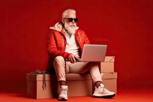 Modern Santa Claus is sitting on a large cardboard gift box on a red background and holding a new book in his hands, . photo
