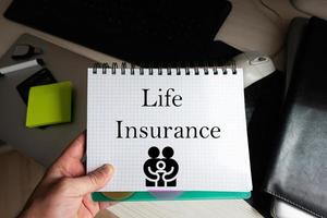 Life insurance word on notebook holding man against desktop. photo