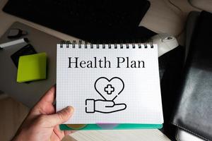 Health plan word on notebook holding man against desktop. photo