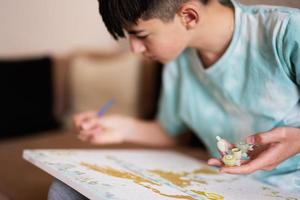 joven masculino adolescente pintura imagen por números en lona en vivo habitación a hogar. pasatiempo y ocio concepto. foto