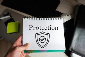 Protection word on notebook holding man against desktop. photo