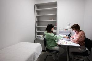 Manicure master working with female client in beauty salon. Manicurist makes woman nail. photo