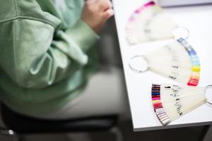 Manicure master working with female client in beauty salon. Woman chooses color of nail polish from palette. photo