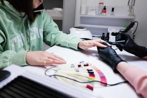 Manicure master working with female client in beauty salon. Manicurist makes woman nail. photo