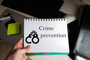 Crime prevention word on notebook holding man against desktop. photo