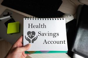 Health savings account word on notebook holding man against desktop. photo