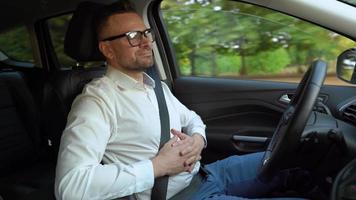 barbado hombre en lentes y blanco camisa conducción un coche en soleado clima video