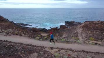 Aerial view of woman runs along the oceanfront nature reserve at sunrise. Healthy active lifestyle video