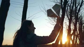 Woman launches paper airplane against sunset background. Concept of wanting to go on vacation or travel. Slow motion video