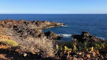 Zeitraffer von ein verlassen Küste und Meer Wellen erreichen Ufer. felsig Ufer von das Insel von Tenerife video