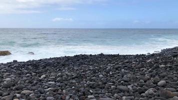 espaço de tempo do uma ampla seixo de praia e oceano ondas alcançando costa. rochoso costa do a ilha do tenerife video