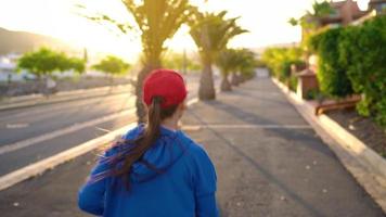 femme attacher les lacets et départs le jogging le long de le rue parmi le tropical ruelle. en bonne santé actif mode de vie video