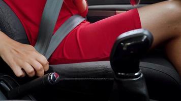 Woman in red dress fastening car safety seat belt while sitting inside of vehicle before driving video