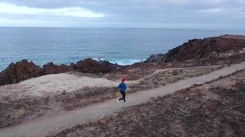 Aerial view of woman runs along the oceanfront nature reserve at sunrise. Healthy active lifestyle video