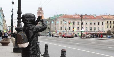 Sankt Petersburgo Rusia - 04 19 2023 encantador hembra con miedoso Mira haciendo foto en célula teléfono mientras en pie cerca arquitectónico Monumento en urbano ajuste