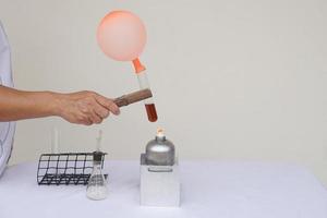 Closeup man is demostrating science exeriment about reaction of balloon on test tube is burned from lantern. The expanding of air pressure, reaction of chemical substance. Concept, Science activity. photo