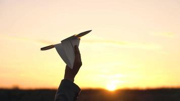 mulher lançamentos papel avião contra pôr do sol fundo. conceito do querendo para ir em período de férias ou viagem. lento movimento video