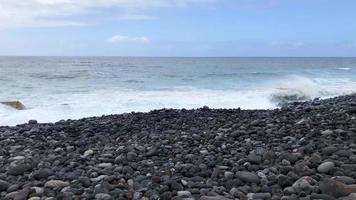 timelapse van een groot kiezelsteen strand en oceaan golven bereiken oever. rotsachtig kust van de eiland van Tenerife video