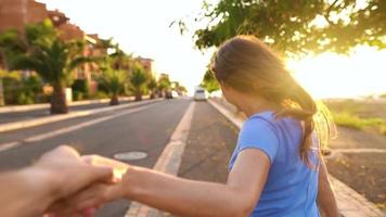 seguir yo - contento joven mujer tracción tipo mano - mano en mano corriendo en un brillante soleado día. lento movimiento video