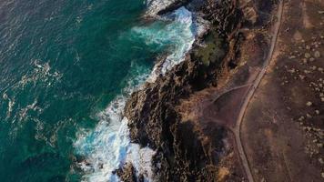 topp se av en folktom kust. klippig Strand av de ö av teneriffa. antenn Drönare antal fot av hav vågor nå Strand video