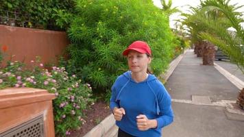 Woman jogging along the street among the tropical alley video