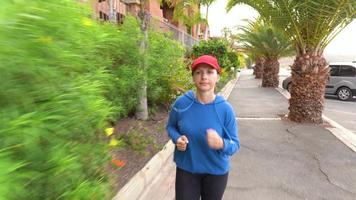 vrouw jogging langs de straat tussen de tropisch steeg video