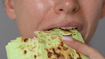 Woman eating spinach shawarma with chicken and vegetables close-up video