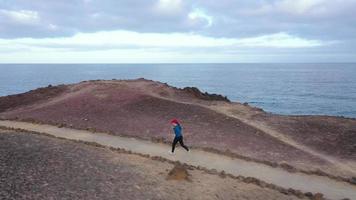 Aerial view of woman runs along the oceanfront nature reserve at sunrise. Healthy active lifestyle video