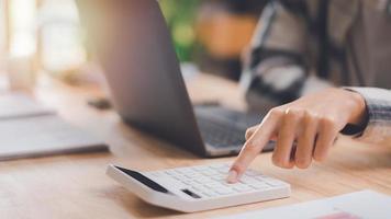 Businessman using a calculator to calculate numbers ,profit and loss statement review of company performance ,cost analysis ,business account checking ,Annual budget management planning photo