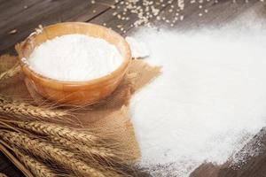 Soft focus, flour in a wooden bowl, ears of wheat, barley, cooking, bread, and cookies arranged on a wooden tabletop in a rustic kitchen, top view. photo