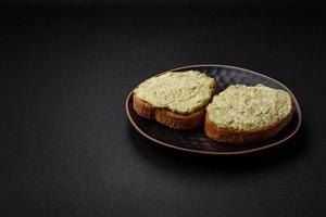 Grilled toast with avocado paste, eggs, cream cheese, salt, spices and herbs photo