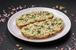 Grilled toast with avocado paste, eggs, cream cheese, salt, spices and herbs photo