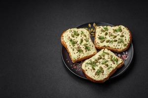 Grilled toast with avocado paste, eggs, cream cheese, salt, spices and herbs photo