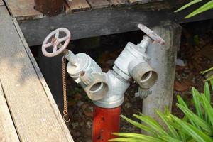 antiguo rojo fuego boca de aguas en el jardín. grifo agua para agua suministrar. foto