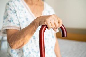 Asian elderly disability woman holding waling stick, wood cane, round handle, walking aid for help to walk. photo