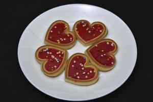 Red heart cookies on a white plate. Sweet cookies with a heart. photo