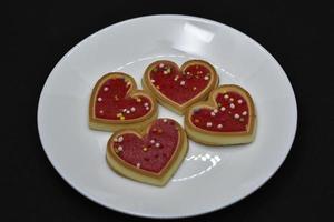 Red heart cookies on a white plate. Sweet cookies with a heart. photo