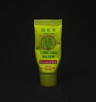 Jakarta, Indonesia - April 21th, 2023 - Tjing Tjau muscle paint relievement medical hot cream product with yellow packaging tube. Product photography isolated on plain black background. photo