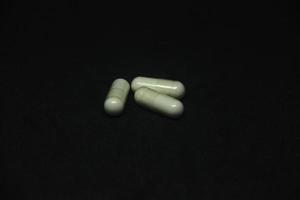 amarillo vegetal tableta medicina suplemento para enfermedades y diario cuidado de la salud. un manojo de pastillas fotografía aislado en oscuro negro antecedentes. foto