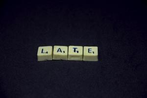 Alphabet english word with late saying or spelling photography. Word block isolated on dark horizontal black background. Simple business image themed idea concept photo. photo