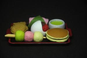 borrador con japonés dulce postre comida formas desde dorayaki, taiyaki, sakura mochi, dango, ocha colegio herramienta para borrando suministros equipo fotografía aislado en oscuro negro horizontal antecedentes. foto