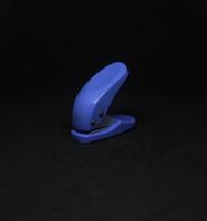 Jakarta, Indonesia - April 21th, 2023 - Deli small blue hole puncher portable easy to carry stationary tools photography isolated on dark black background. photo