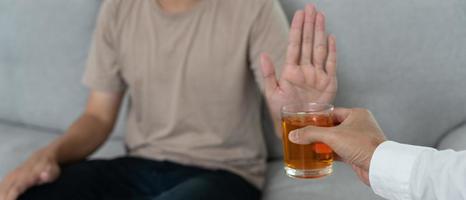 man refuses say no and avoid to drink an alcohol whiskey , stopping hand sign male, alcoholism treatment, alcohol addiction, quit booze, Stop Drinking Alcohol. Refuse Glass liquor, unhealthy, reject photo