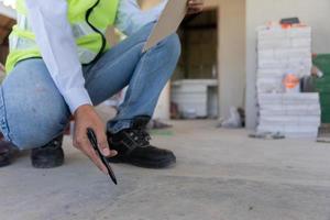 el inspector o ingeniero está inspeccionando la construcción y el aseguramiento de la calidad de la nueva casa usando una lista de verificación. ingenieros o arquitectos o contratistas trabajan para construir la casa antes de entregársela al propietario foto